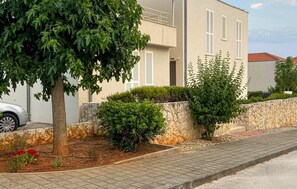 Ein modernes Gebäude mit einer Steinsichtmauer, einem gepflasterten Bürgersteig und einem Baum.