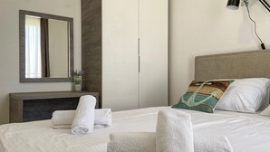 Una habitación de hotel con una cama, una mesita de noche, un espejo y una mesilla.