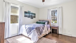 A bedroom with a bed, a nightstand, a ceiling fan, and two windows with curtains. - Waterfront home with dock, pool and hot tub! NOTRE DAME FOOTBALL (Osceola)