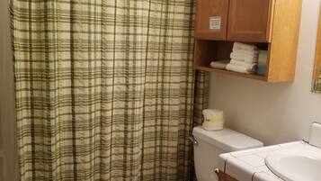 Ein Badezimmer mit gestreiftem Duschvorhang, Toilette und Holzausbau.