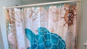 Une salle de bain avec un rideau de douche orné d’un motif représentant une tortue de mer.