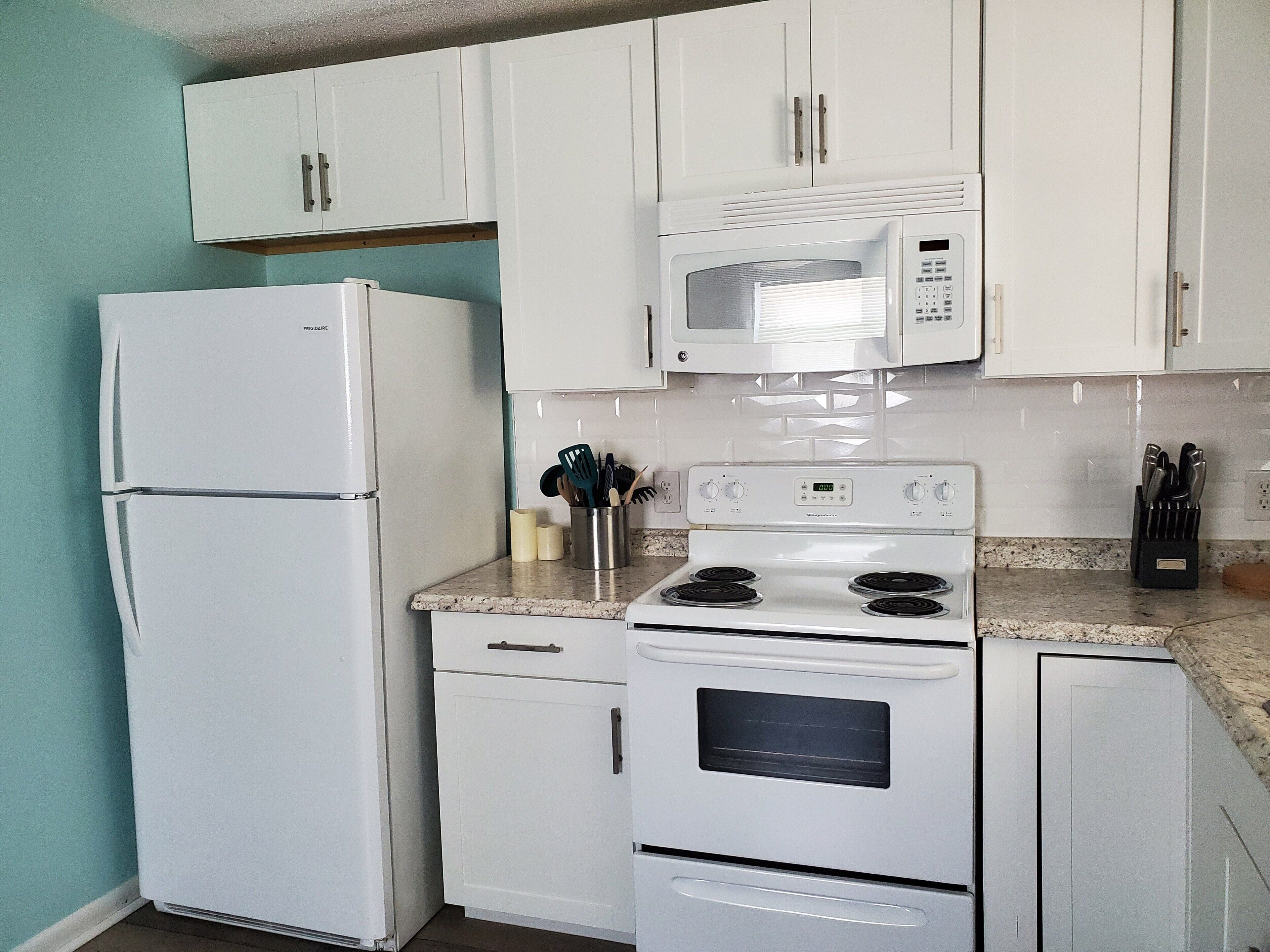 A kitchen with white appliances, including a refrigerator, microwave, stove, and oven.