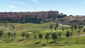 Un campo de golf con un edificio grande al fondo.