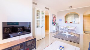 Una sala de estar moderna con televisor, sofá y un mueble con puertas de vidrio.