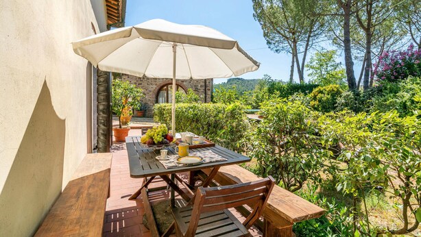 An outdoor patio with a table, chairs, and a large umbrella. - Cozy apartment in Molino del Piano (Molino del Piano)