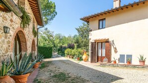 A courtyard with a gravel path, potted plants, and a building with stone and stucco walls. - Cozy apartment in Molino del Piano (Molino del Piano)