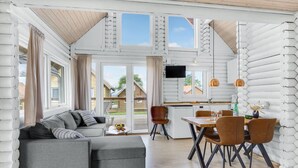 A modern log cabin interior with a dining area, sofa, and TV. - Lovely home in Tranekær (Tranekær)