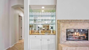 Una cocina con armarios blancos, una vitrina con puerta de vidrio y una chimenea.