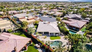 Vista aérea de una zona residencial con casas, una piscina y un edificio grande con techo plano.