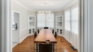 A dining area with a long wooden table, black chairs, and a chandelier.