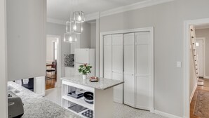 A modern kitchen with a marble countertop, a built-in oven, and a hanging light fixture.