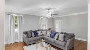 A modern living room with a grey sectional sofa, a glass coffee table, and a ceiling fan.