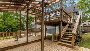 A wooden deck with a covered area and a staircase leading to an upper level.