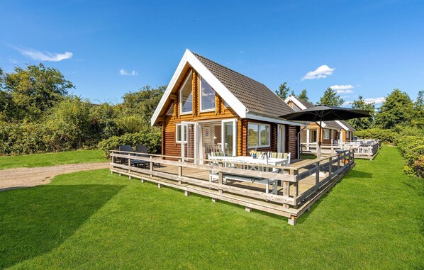 Une cabane en bois dotée d’une terrasse, d’un espace salon extérieur et d’un patio couvert.