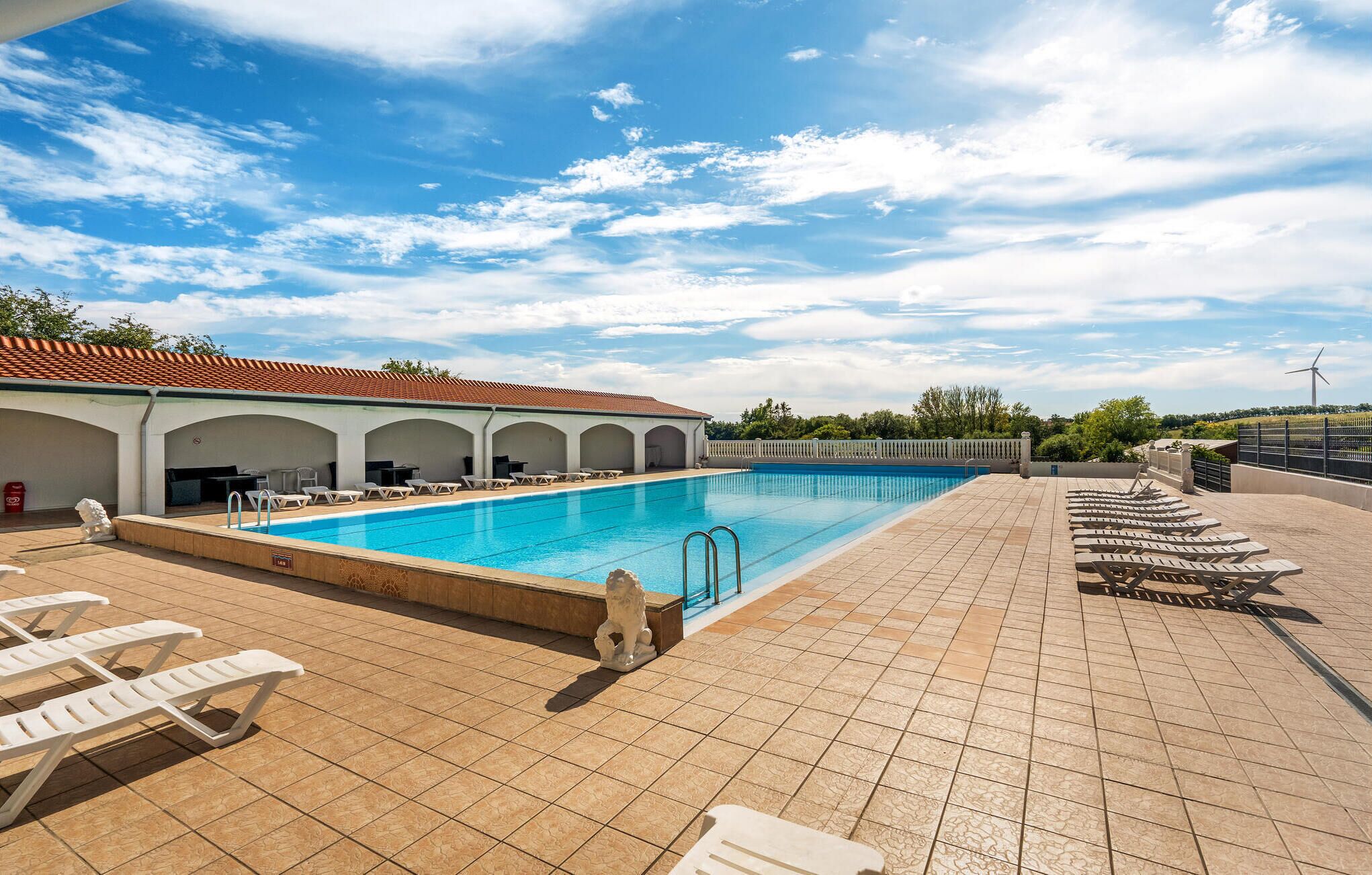 A swimming pool with lounge chairs and a covered seating area.