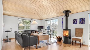 Un salon moderne doté d’une cheminée, d’un plafond en bois et de grandes fenêtres.