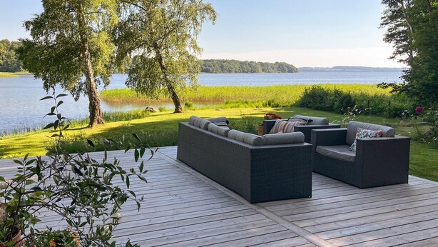 A deck with outdoor furniture overlooking a lake.