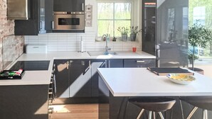 A modern kitchen with a built-in oven, a window with plants, and a white countertop.