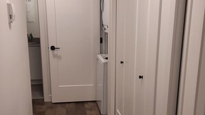 A hallway with wooden flooring, white walls, and closed doors. - Adorable 1 bed room legal basement suite (Saskatoon)