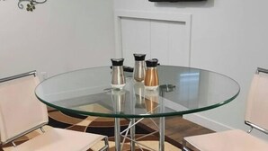 A round glass table with metal legs, surrounded by four white cushioned chairs. - Adorable 1 bed room legal basement suite (Saskatoon)