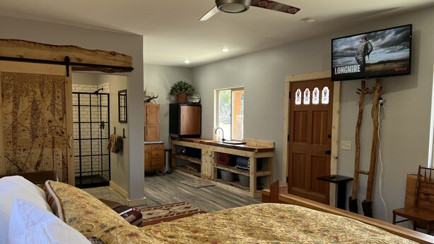 Un dormitorio con una cama grande, un escritorio de madera, un televisor y una puerta con vidrieras.