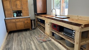 Una cocina compacta con armarios de madera, un microondas integrado y un lavamanos.