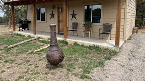 Una cabaña rústica con un porche, una parrilla y dos sillas.