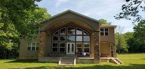A two-story house with a stone facade, large windows, and a covered porch. - Secluded Lakefront Retreat on 60 Acres Private Dock, Fishing & Wildlife (Gravois Mills)