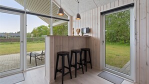 Une cuisine moderne agrémentée d’éléments en bois, un coin bar avec des tabourets et de grandes fenêtres offrant une vue sur l’extérieur.