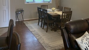 A dining area with a table set for four, a chandelier, and a 'be our guest' sign on the wall. - 2 bedroom condo in osage beach (Osage Beach)