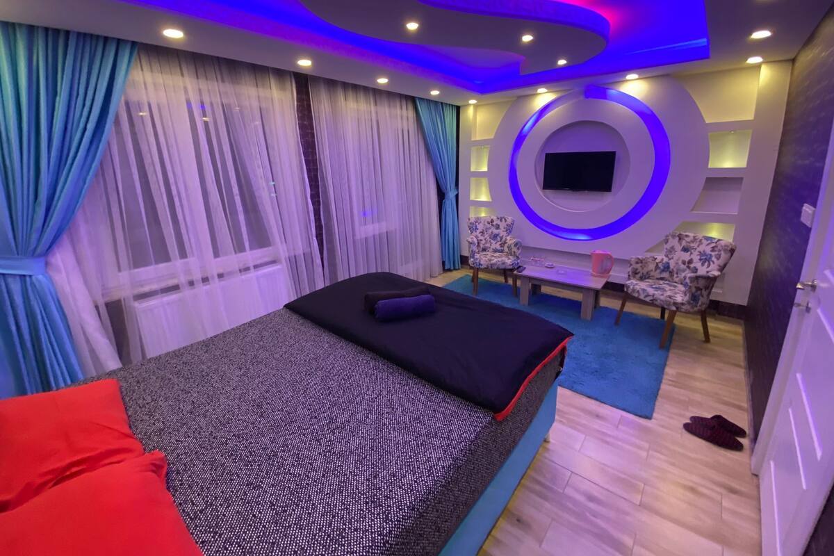 A modern bedroom with a bed, a TV, and a seating area.