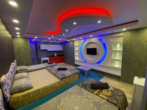 A modern hotel room with a sofa, a small table, and a TV mounted on the wall. - Haznedar Luxury Residence Hotel (Istanbul)