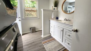 Une salle de bain moderne dotée d’un lave-linge et d’un sèche-linge intégrés, d’un meuble-lavabo et d’un grand miroir.