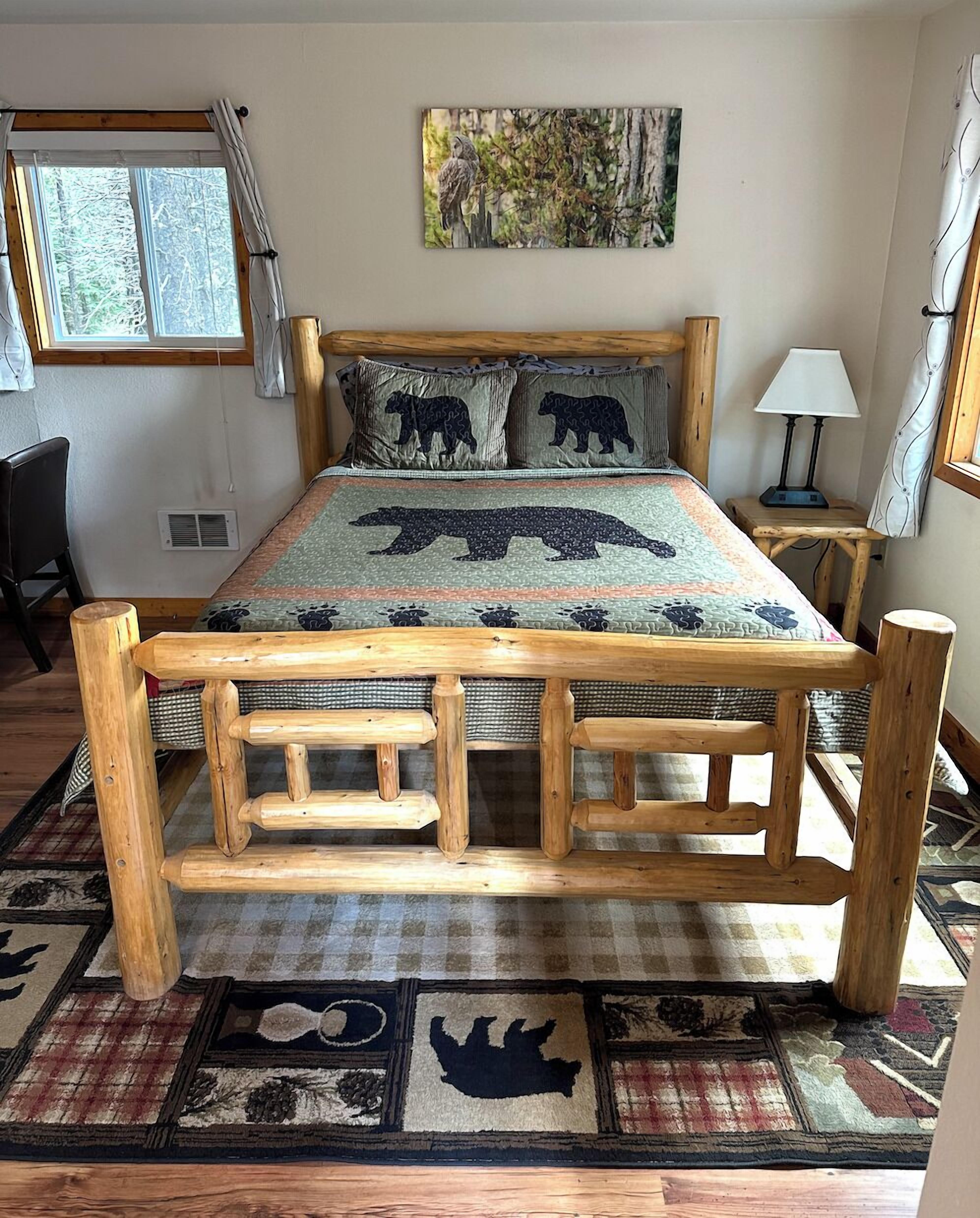 Un lit en bois avec une couvre-lit à motifs d’ours, une fenêtre avec des rideaux, une lampe et un tapis à motifs animaliers.