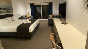 Ein Hotelzimmer mit Bett, Schreibtisch, Stuhl, Fernseher und einem Balkon mit Blick.