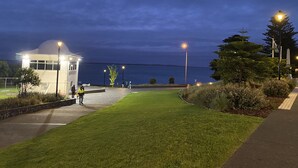 Ein gut beleuchteter Weg führt zu einem kleinen Gebäude mit Kuppeldach, umgeben von Grün und mit Blick auf das Meer.
