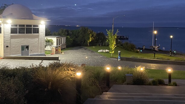 Ein modernes Gebäude mit Kuppel, gepflastertem Bereich und Blick auf das Meer.