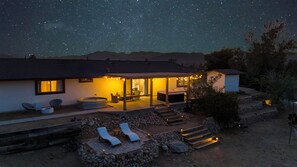 Et hus med overdækket terrasse, udendørs møbler og en jacuzzi.