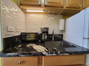 Kitchen features a granite countertop, toaster oven, and coffee maker.
