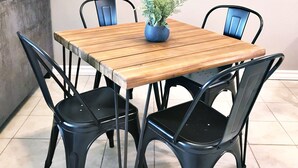 A dining table with four chairs, a potted plant, and a decorative wall piece.