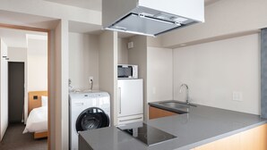 Uma cozinha compacta com máquina de lavar embutida, micro-ondas e pia.