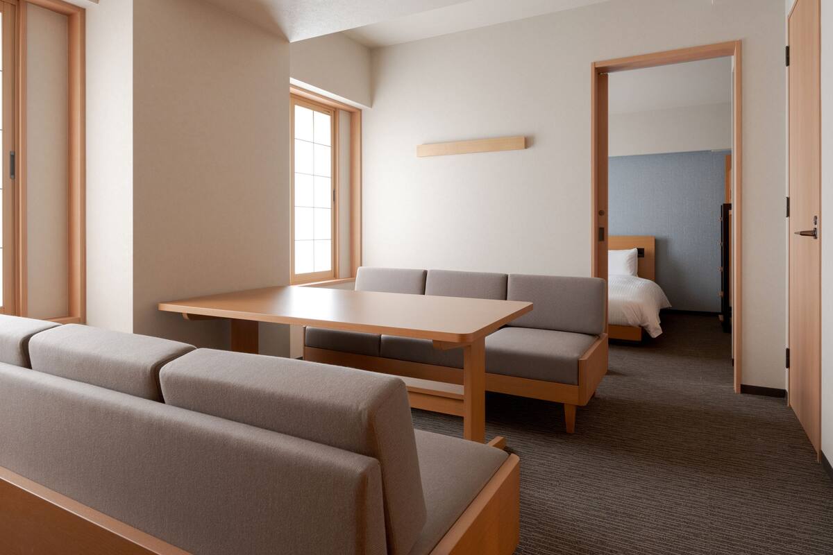 A modern hotel room with a sofa, a small table, and a bed.