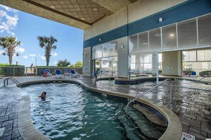 A swimming pool area with a tiled deck, a child playing in the water, and lounge chairs. - 635 Seas the Day. (Myrtle Beach)