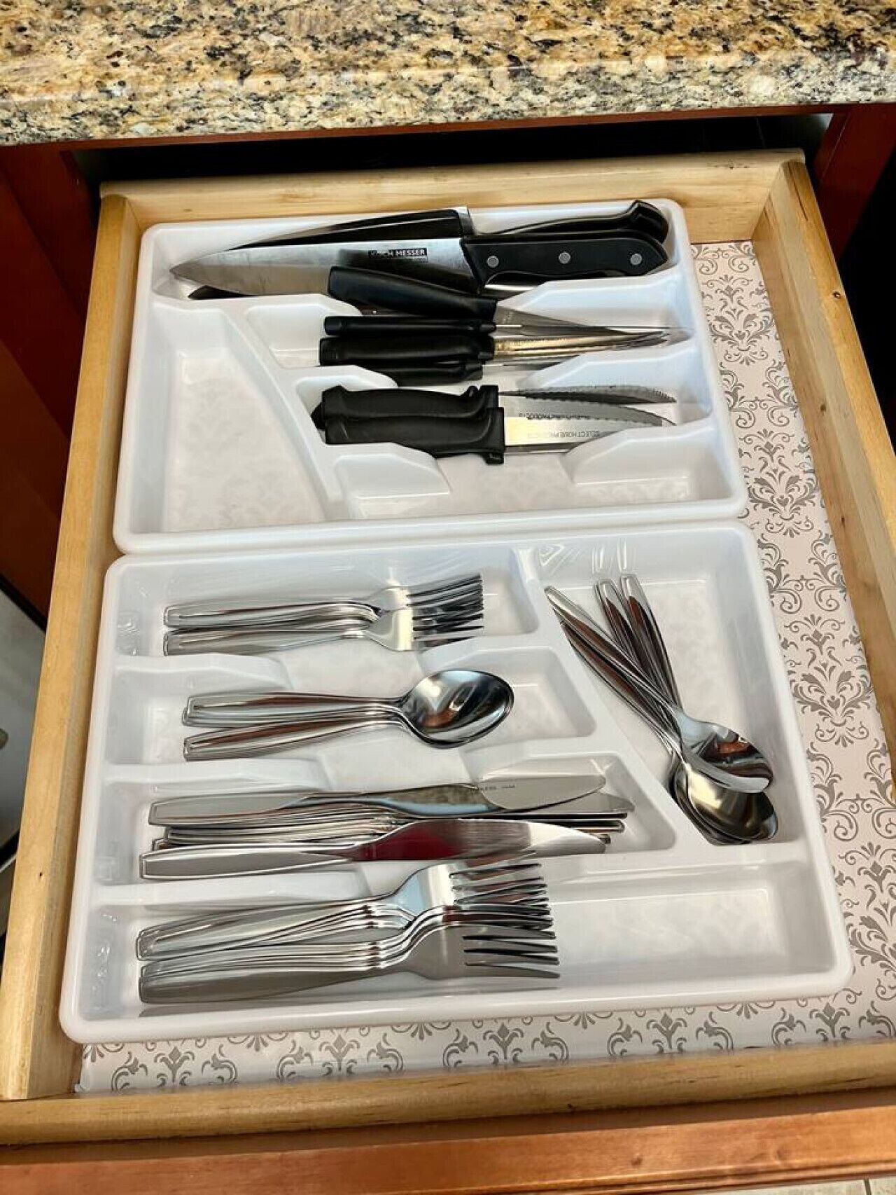 A drawer with compartments containing various kitchen utensils.
