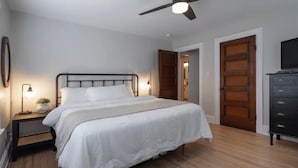 Een slaapkamer met een bed, bedlampen, een plafondventilator en een dressoir.