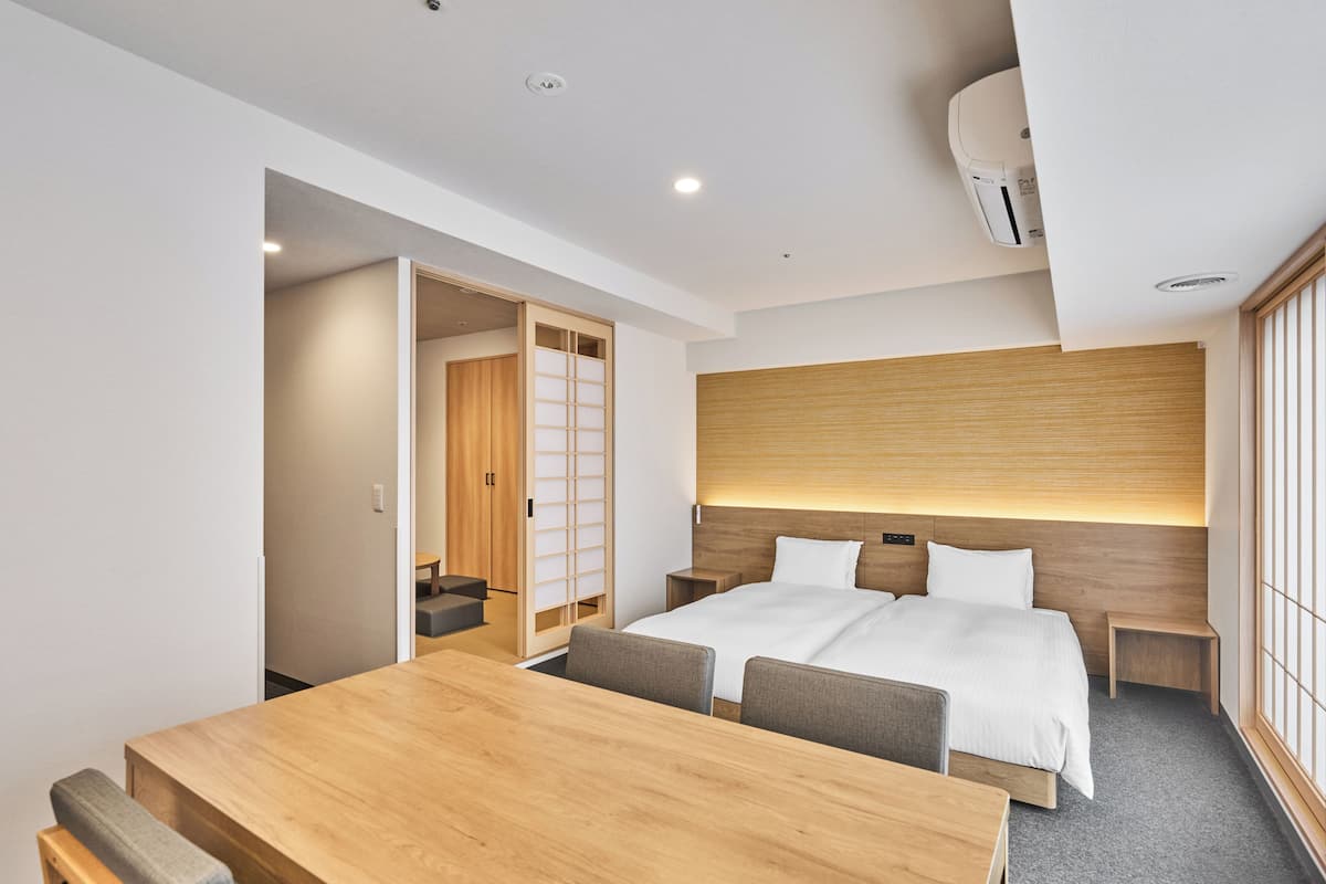 A modern hotel room with a wooden bed, a wooden desk, and a sliding door closet.