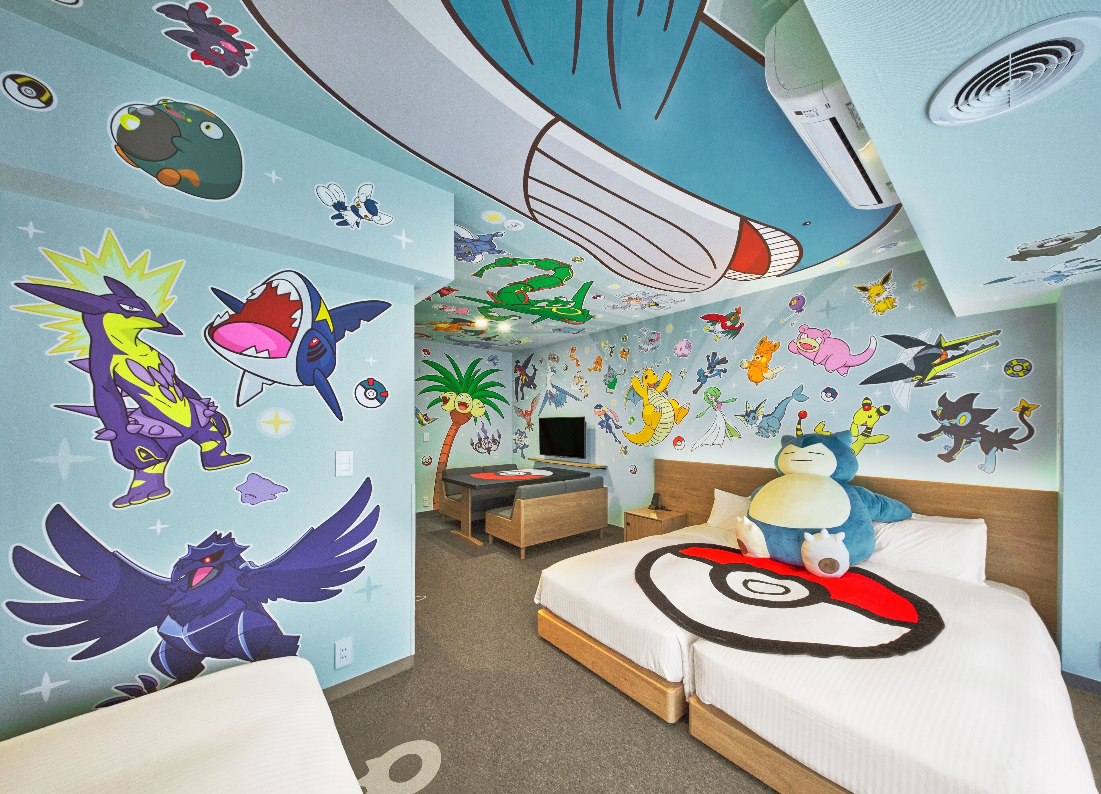 A hotel room with a large bed, a desk, and a ceiling with colorful wall decals.