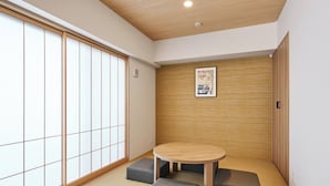 A traditional Japanese room with tatami flooring, a shoji screen door, a round table with cushions, and a wooden panel wall. - MIMARU Tokyo Kinshicho (Tokyo)