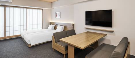 A modern hotel room with a bed, a TV mounted on the wall, and a small wooden table.