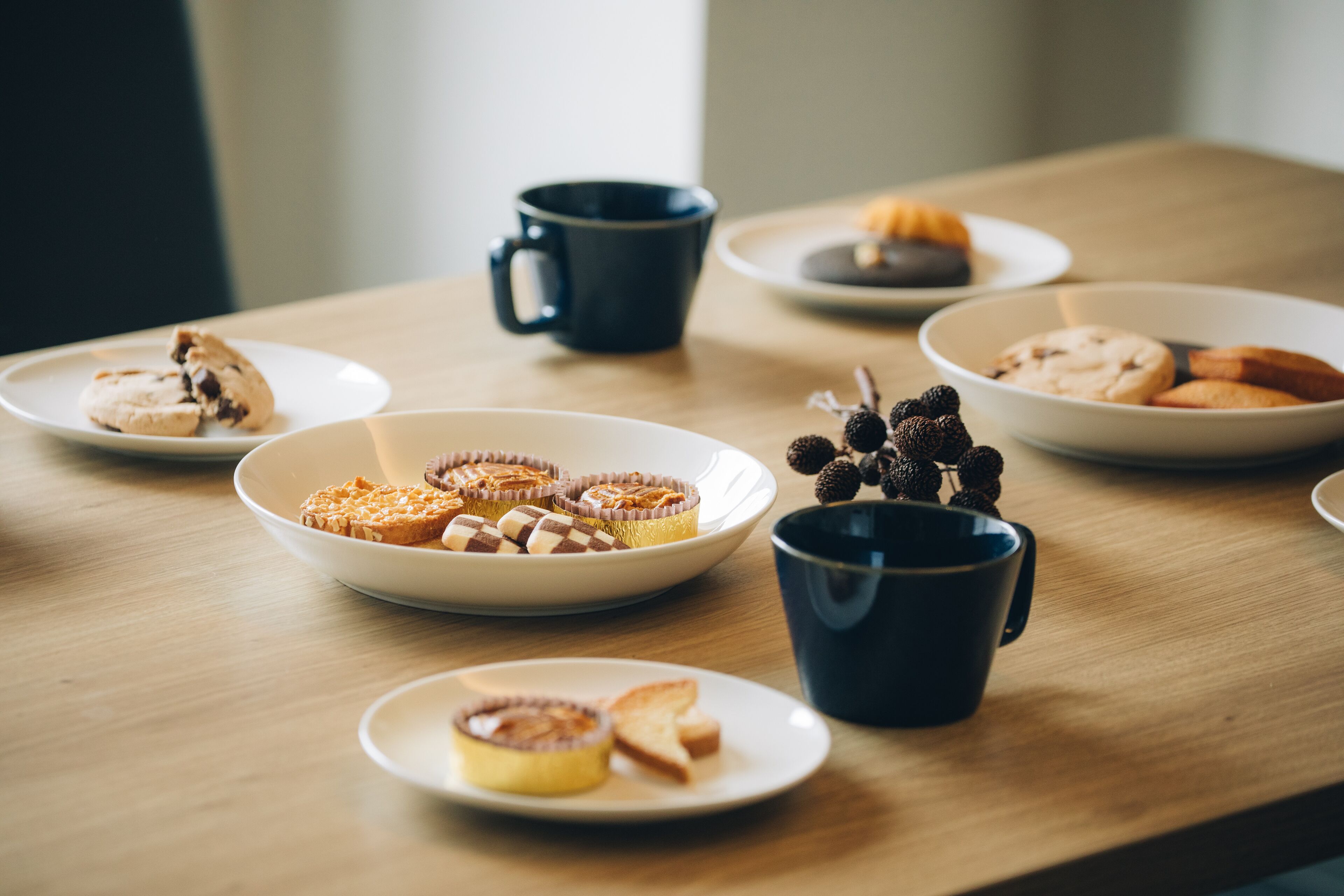 Ein Holztisch mit verschiedenen Frühstücksleckereien, darunter Gebäck, Kekse und einer Kaffeetasse.